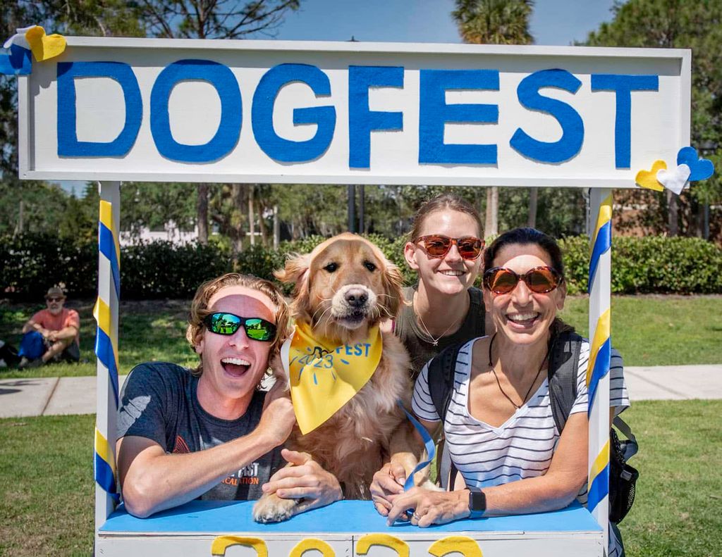Four people pose cheerfully in a photo booth marked